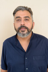 Portrait of bearded Indian businessman against plain background