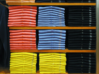 Colorful orderly folded fabric studs T- shirt on the shelf with size label