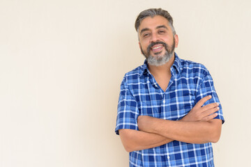 Portrait of bearded Indian businessman smiling against plain background