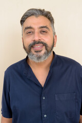 Obraz premium Portrait of bearded Indian businessman smiling against plain background