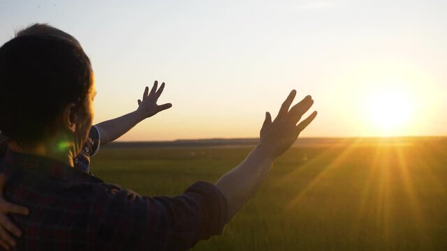 happy family father and son are pulling teamwork hands to the sun. dad and little boy cuddle stand back to sunset. happy lifestyle family parent and kid silhouette pat childhood concept