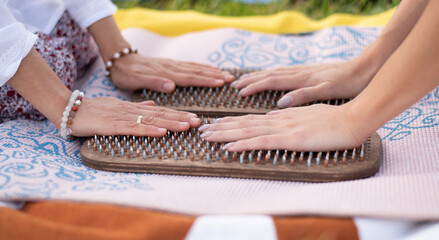 hands of two Women  lies on wooden board with metal nails for sadhu practice. Outdoor. Closeup. Yoga in couple, practice forgiveness. Sharp metal nails.