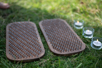 Wooden board with nails for sadhu practice. Outdoor on green grass with candles. Yoga practice with sharp nails for forgiveness and overcome fears.