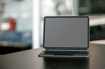 Mockup blank screen portable tablet with magic keyboard on wooden table