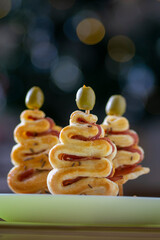 Salty puff pastry bakery with cheese, ham and green olives on the top, group of Christmas tree shapes