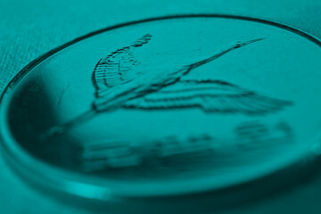 Translation: 500 won. Korean coin close up. Obverse with the image of a crane. Dark turquoise tinted background or wallpaper on economic, financial or banking theme. Money and business in South Korea