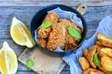
 Crispy  deep fried   chicken strips and Wings ,onions and Wedges potatoes  Breaded  with cornflakes chicken  breast fillets  with chilly peppers and fresh   basil on wooden rustic background