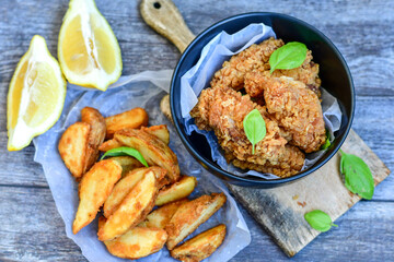 
 Crispy  deep fried   chicken strips and Wings ,onions and Wedges potatoes  Breaded  with cornflakes chicken  breast fillets  with chilly peppers and fresh   basil on wooden rustic background