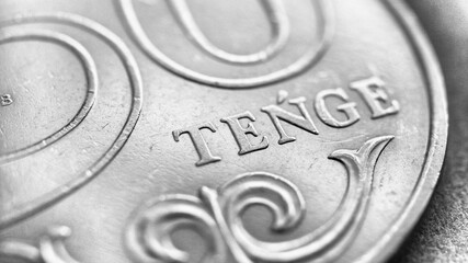 Translation: tenge. Fragment of a Kazakh coin in 50 tenge. Black and white background or wallpaper. The name of the currency in Latin. Wallpaper about Kazakh economy, money and taxes. Macro