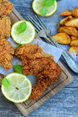 
 Crispy  deep fried   chicken strips ,onions and Wedges potatoes  Breaded  with cornflakes chicken  breast fillets  with chilly peppers and fresh   basil on wooden rustic background