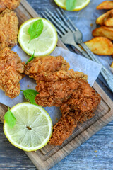 
 Crispy  deep fried   chicken strips ,onions and Wedges potatoes  Breaded  with cornflakes chicken  breast fillets  with chilly peppers and fresh   basil on wooden rustic background