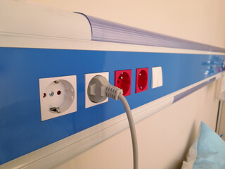 power cord plugged into electrical outlet on insulated wall in hospital room