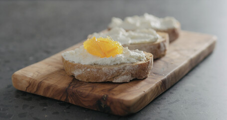 sweet bruschetta with orange marmalade and ricotta on olive board