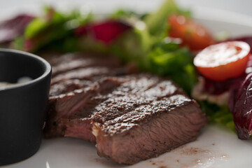 ribeye steak with garlic sauce and fresh salad closeup