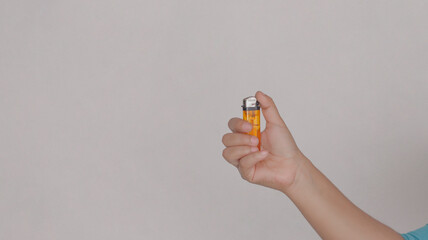 lighter on gray background. Hand holding orange lighter in white background