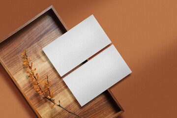 Clean minimal business card mockup on wooden plate with autumn plant