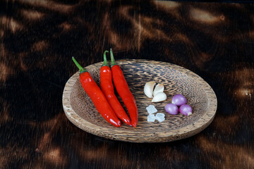 red chilies and fresh onions on a tray with dark wooden background