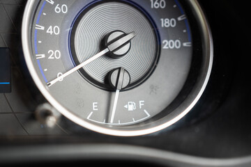 Vehicle fuel level indicator gauge while showing only few gasoline is remaining in the tank. Transportation equipment object photo. Close-up and selective focus at the index gauge.