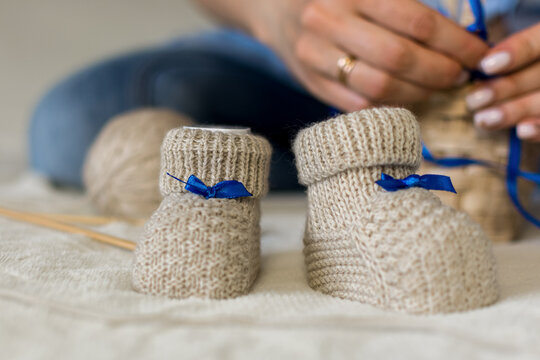 White Baby Booties With A Blue Ribbon. Close-up.