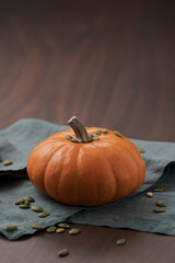 pumpkin seeds on orange pumpkin on walnut table with linen cloth with copy space