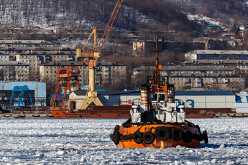 Sea tug boat goes along the Nakhodka Bay among coal heaps.