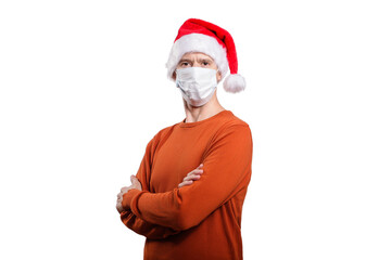 an isolated shot of a happy man in a medical mask from the coronavirus, in casual clothes, an orange sweater, a Christmas hat. He crossed his arms on his chest, looking into the camera