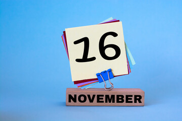 November 16th. Day 16 of November month, calendar on workplace with blue background. Autumn time.