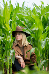 Blonde woman in cloak and hat in cornfield in summertime