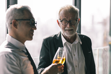 Picture of young business man taking to his older business partner. They are in white shirt and black tie. They are in a hotel lobby. 