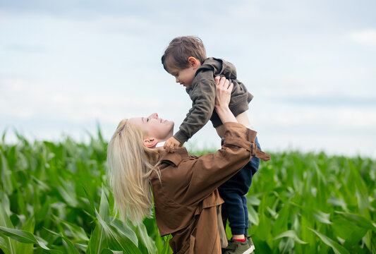 Blonde mother in cloak with a child boy in cornfield in summertime