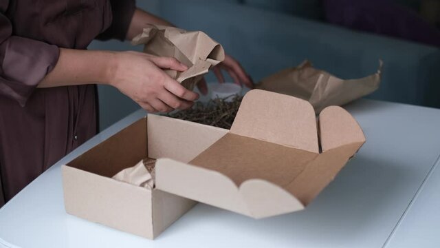 woman is packing jars of cosmetics in a box to send a parcel through a delivery service.