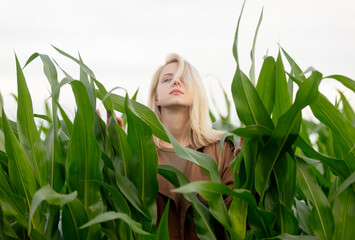 Blonde woman in cloak in cornfield in summertime