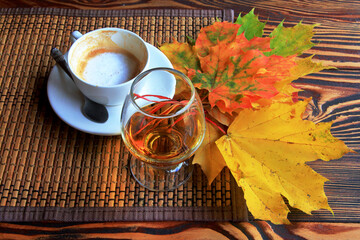 Autumn still life with cup of coffee, brandy and leaves.