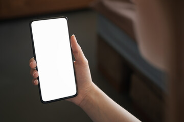 Young woman hold smartphone with white screen while sitting on a couch
