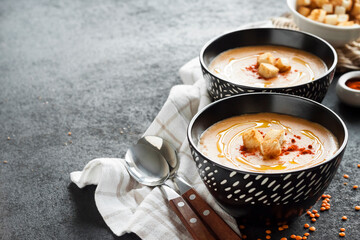 Lentil cream soup with paprika and crouton in black ceramic bowls