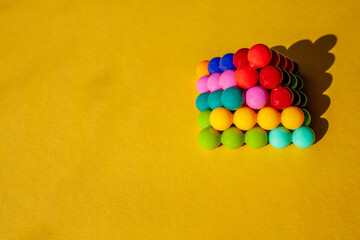 pyramid of multi-colored bright plastic parts with shadow on yellow background