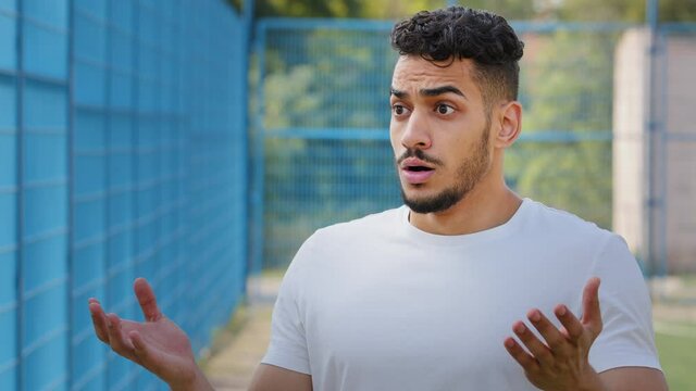 Afraid surprised indignant Middle Eastern Arab athlete in summer sportswear frantically gesturing expressing displeasure, outrage and disagreement. Indian millennial outraged by situation at stadium