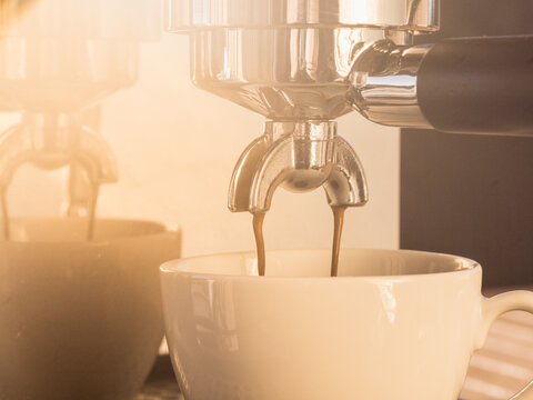 espresso coffee pouring from espresso machine - nice lense flare - Powered by Adobe