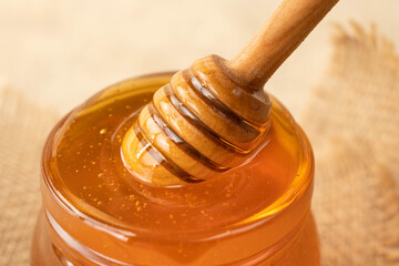 Liquid Honey on Special Spoon in Wooden Bowl Close Up. Harvest beekeeping. Golden fresh honey is pouring from stick. Honey Dripping to Honey Dipper. Concept of healthy food and sweet meals