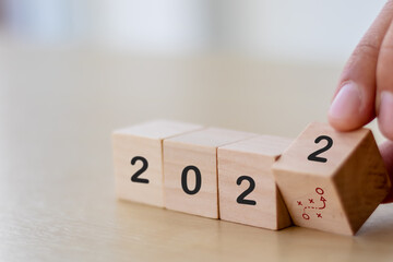 Business strategy and game plan in 2022 concept. Businessman hand flips wooden cubes "2022" and "strategy" symbol  on beautiful  background and copy space. For annual and action plan in the new year.