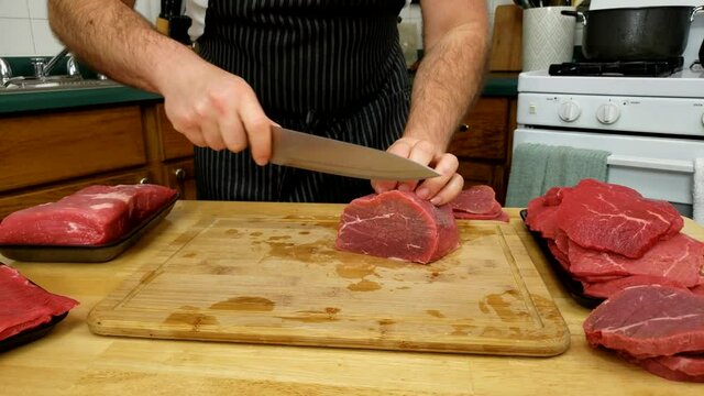 Home cooking - Round eye beef being cut into thick slices preparing meat for jerky or cooking.