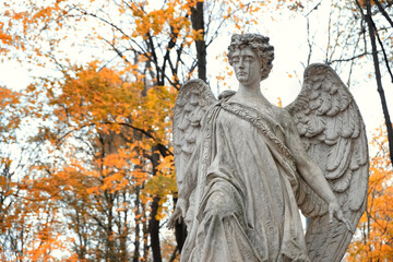 Angel statue on old cemetery, autumn natural background. concept of religion, faith, Remember, mourn, memory. all saints day, All Souls Day. Design for condolences, mourning cards or obituary