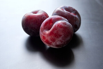 Ripe red plums on a dark background
