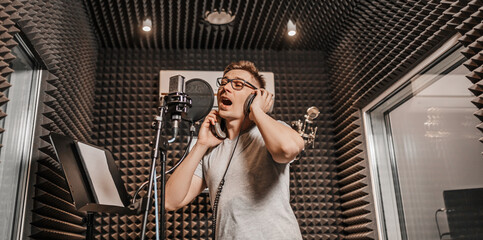 The vocalist sings in the studio in a microphone. Man in headphones writes a podcast, an audiobook....