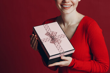Young woman holding christmas gift box with ribbon. Studio shot portrait