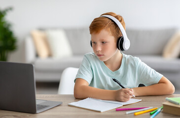 Redhead boy schooler having online lesson from home - obrazy, fototapety, plakaty