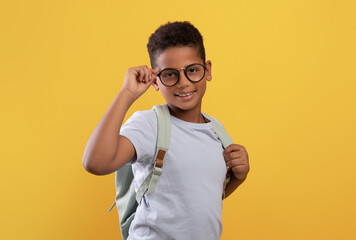 Happy african american school boy with glasses and backpack