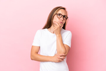 Young English woman isolated on pink background having doubts