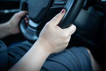 Young woman holding steering wheel with hands while driving a car