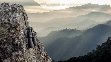 Binocular on top of rock mountain at sunset
